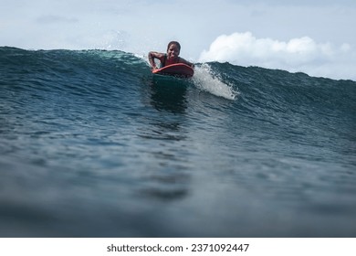 Young black woman surfing a wave getting ready to stand on surfboard and riding waves in Sao Tome and Principe, Africa - Powered by Shutterstock