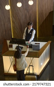 Young Black Woman Taking Back Her Passport Being Passed By Hotel Manager In Uniform After Registration By Reception Counter