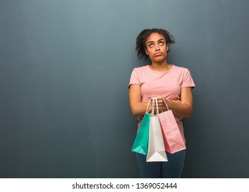 Young Black Woman Tired And Bored. She Is Holding A Shopping Bags.