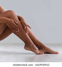 Young black woman touching silky skin on legs after epilation, grey background - Shutterstock ID 1619935912