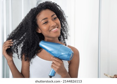 Young Black Woman Using A Hair Dryer In Front Of Mirror