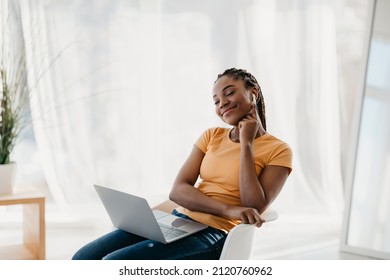 Young Black Woman Using Laptop Computer, Wearing Earphones, Relaxing With Closed Eyes At Home. Happy African American Lady Listening To Music Or Audio Book On Portable Pc