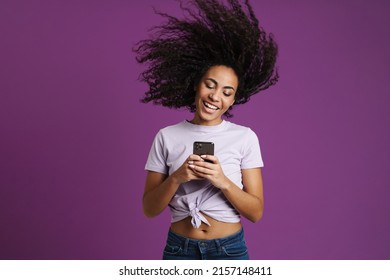 Young Black Woman Using Mobile Phone While Making Fun Isolated Over Purple Background