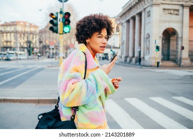 Young black woman walking outdoors using smartphone sending vocal instant message 