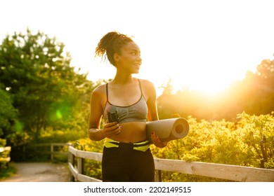 Young Black Woman Walking With Yoga Mat After Practice In Summer Park Outdoors