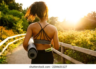 Young Black Woman Walking With Yoga Mat After Practice In Summer Park Outdoors