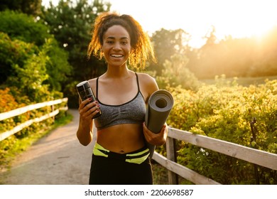 Young Black Woman Walking With Yoga Mat After Practice In Summer Park Outdoors