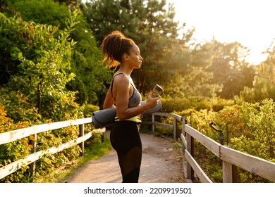 Young Black Woman Walking With Yoga Mat After Practice In Summer Park Outdoors