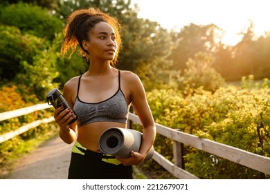 Young Black Woman Walking With Yoga Mat After Practice In Summer Park Outdoors