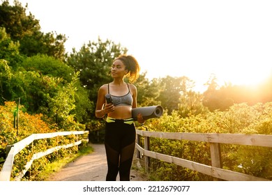 Young Black Woman Walking With Yoga Mat After Practice In Summer Park Outdoors