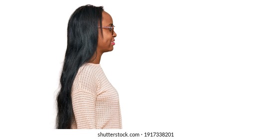 Young Black Woman Wearing Casual Clothes And Glasses Looking To Side, Relax Profile Pose With Natural Face With Confident Smile. 