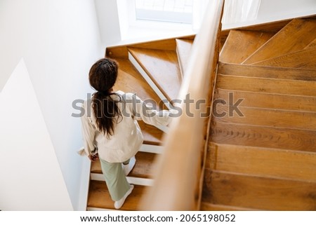 Young black woman wearing pajama walking upstairs at home