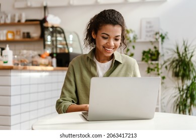 Junge schwarze Frau, die mit Laptop arbeitet, während sie im Café drinnen sitzt