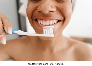 Young Black Woman Wrapped In Towel Brushing Her Teeth At Bathroom