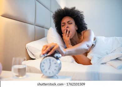 Young Black Woman Yawn Awakening Tired Insomnia Holding Alarm Clock. Wake Up Early In Morning. Girl Stop Snooze Alarm. Female Waking Up Sleepy And Tired. Woman Wake Up With Alarm Clock Snooze Concept.