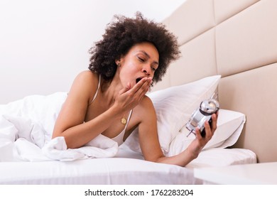 Young Black Woman Yawn Awakening Tired Insomnia Holding Alarm Clock. Wake Up Early In Morning. Girl Stop Snooze Alarm. Female Waking Up Sleepy And Tired. Woman Wake Up With Alarm Clock Snooze Concept.