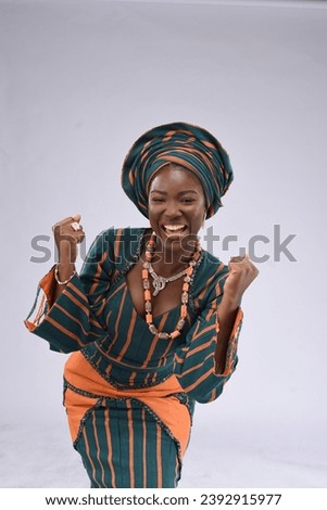 young black yoruba looking gorgeous wearing native attire excited smiling raising up tying gele and surprised feeling happy