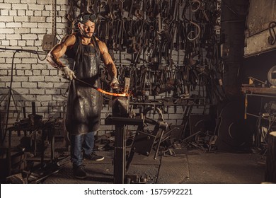 Young Blacksmith Heating Hot Red Metal For Future Manufacturing In Workshop. Forging Industry