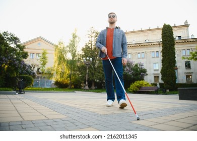 Young Blind Man With White Cane Walking Across The Street In City.