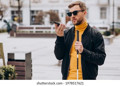 Young blinded man using phone and sending voice message