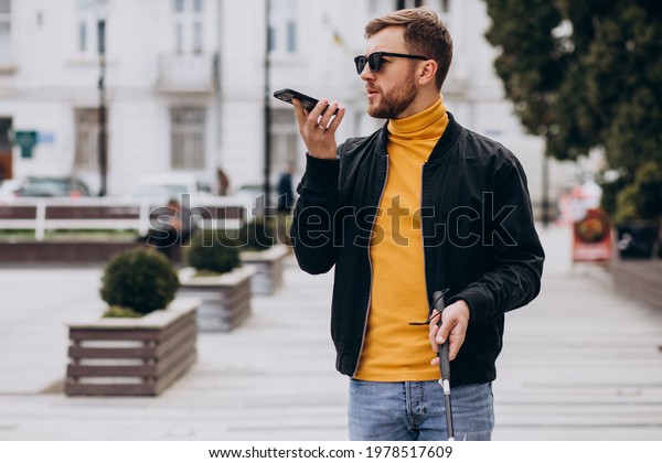Young\
blinded man using phone and sending voice\
message