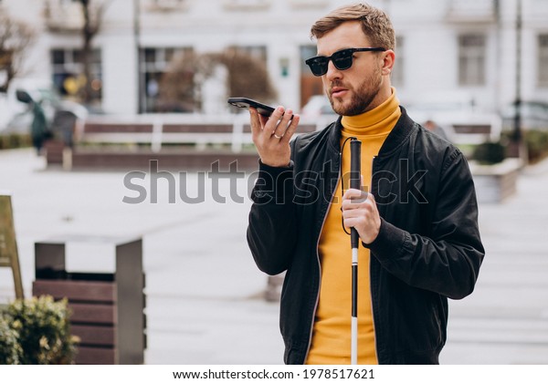 Young\
blinded man using phone and sending voice\
message