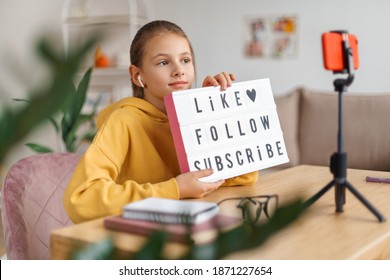 Young blogger girl shooting video for her subscribers and followers from home, showing at camera tablet with text, asking people to like, follow, subscribe her internet channel. Blogging, technology - Shutterstock ID 1871227654