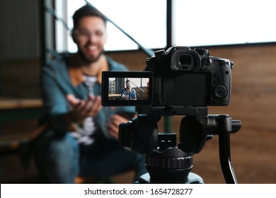 Young blogger recording video indoors, focus on camera screen - Powered by Shutterstock