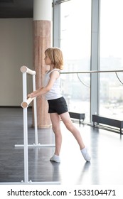 Young blond ballet boy practicing in a studio in white shirt and black underpants ballet uniform