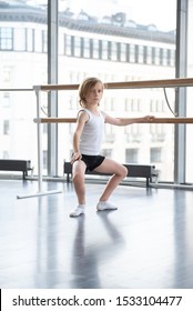 Young blond ballet boy practicing in a studio in white shirt and black underpants ballet uniform