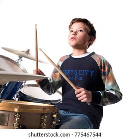 Young Blond Boy At Drum Kit In Studio Against White Background