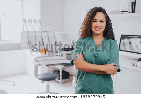 Young blond Caucasian female opening her mouth while African-American ethnic dentist in white latex gloves check condition of her teeth focus on dentist