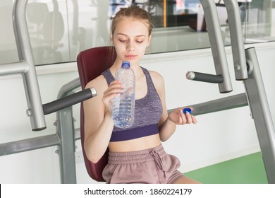Young blond Caucasian sporty girl drinks water in a gym - Shutterstock ID 1860224179