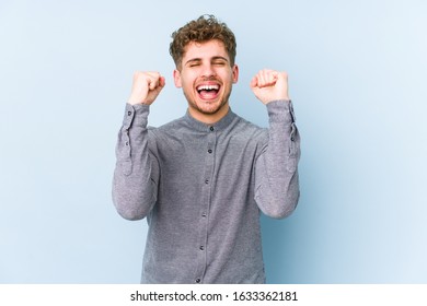 Young blond curly hair caucasian man isolated celebrating a victory, passion and enthusiasm, happy expression. - Shutterstock ID 1633362181