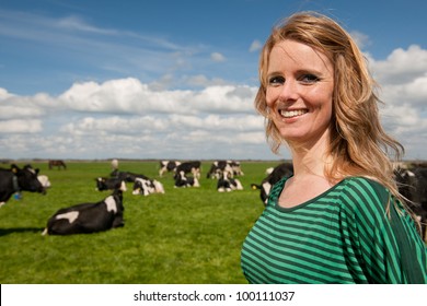 Young blond Dutch girl in farm field with black and white cows