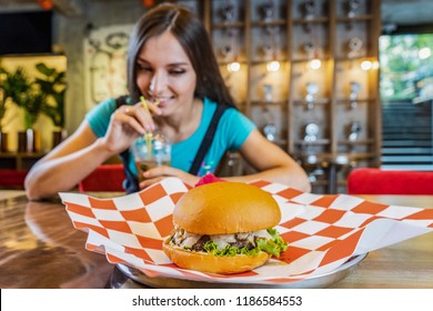 Young Blond Funny Woman Eating A Hamburger At The Outdoor Caf . Puts On A Glove