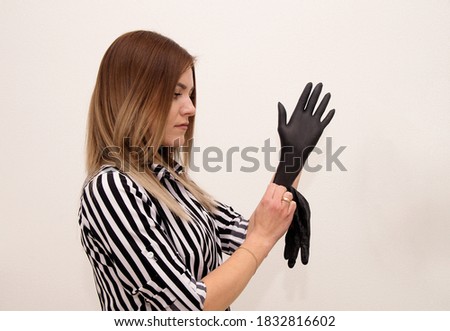 Young blond girl manicurist puts on black gloves