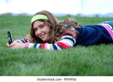 young blond girl in the park and cell phone