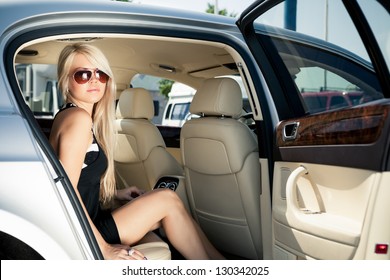 Young Blond Lady Sitting On A Backseat Of A Luxury Car