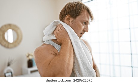 A young blond man with a beard drying off with a towel in a bright home interior. - Powered by Shutterstock