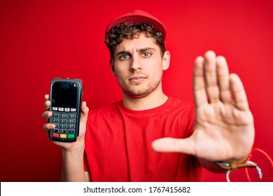 Junge blonde Männer mit lockigen Haaren, die ein Dataphon auf rotem Hintergrund tragen, mit offener Hand Stoppschild mit ernsthaftem und selbstbewusstem Ausdruck, Verteidigungsgeste