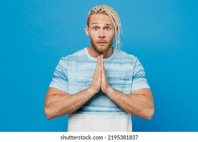 Young Blond Man With Dreadlocks 20s He Wear White T-shirt Hold Hands Folded In Prayer Gesture, Begging About Something Isolated On Plain Pastel Light Blue Background Studio. People Lifestyle Concept