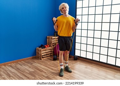 Young Blond Man Smiling Confident Using Elastic Band Training At Sport Center