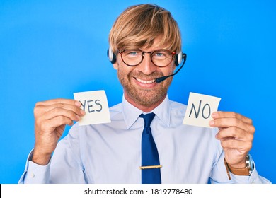 Young Blond Man Wearing Operator Headset Holding Yes And No Reminder Smiling With A Happy And Cool Smile On Face. Showing Teeth. 