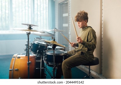 Young Blond Teen Boy Play Drum Kit In Studio.