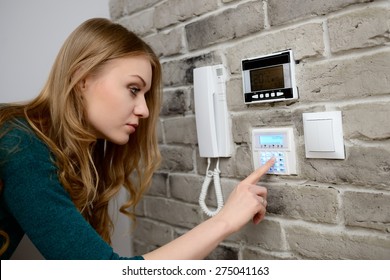 Young Blond Woman Activates An Alarm In The House. Introduces A Code Using The Keypad