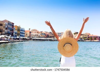 Young Blond Woman In Big Hat Enjoying The Beautiful Views Of The Port Of Chania In Venetian Style. History Architecture Travel. Chania, Crete Island. Greece. 

