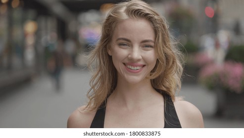 Young blond woman in city face portrait smiling happy