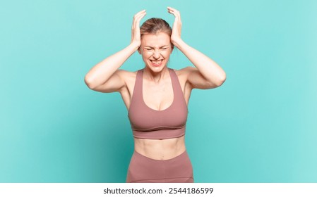 young blond woman feeling stressed and frustrated, raising hands to head, feeling tired, unhappy and with migraine. sport concept - Powered by Shutterstock