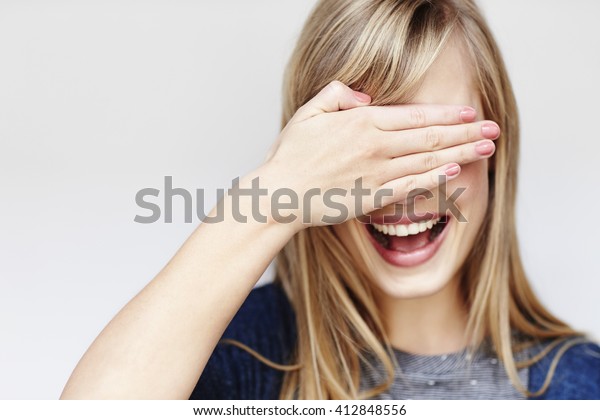 Young blond woman\
with hand over eyes,\
studio